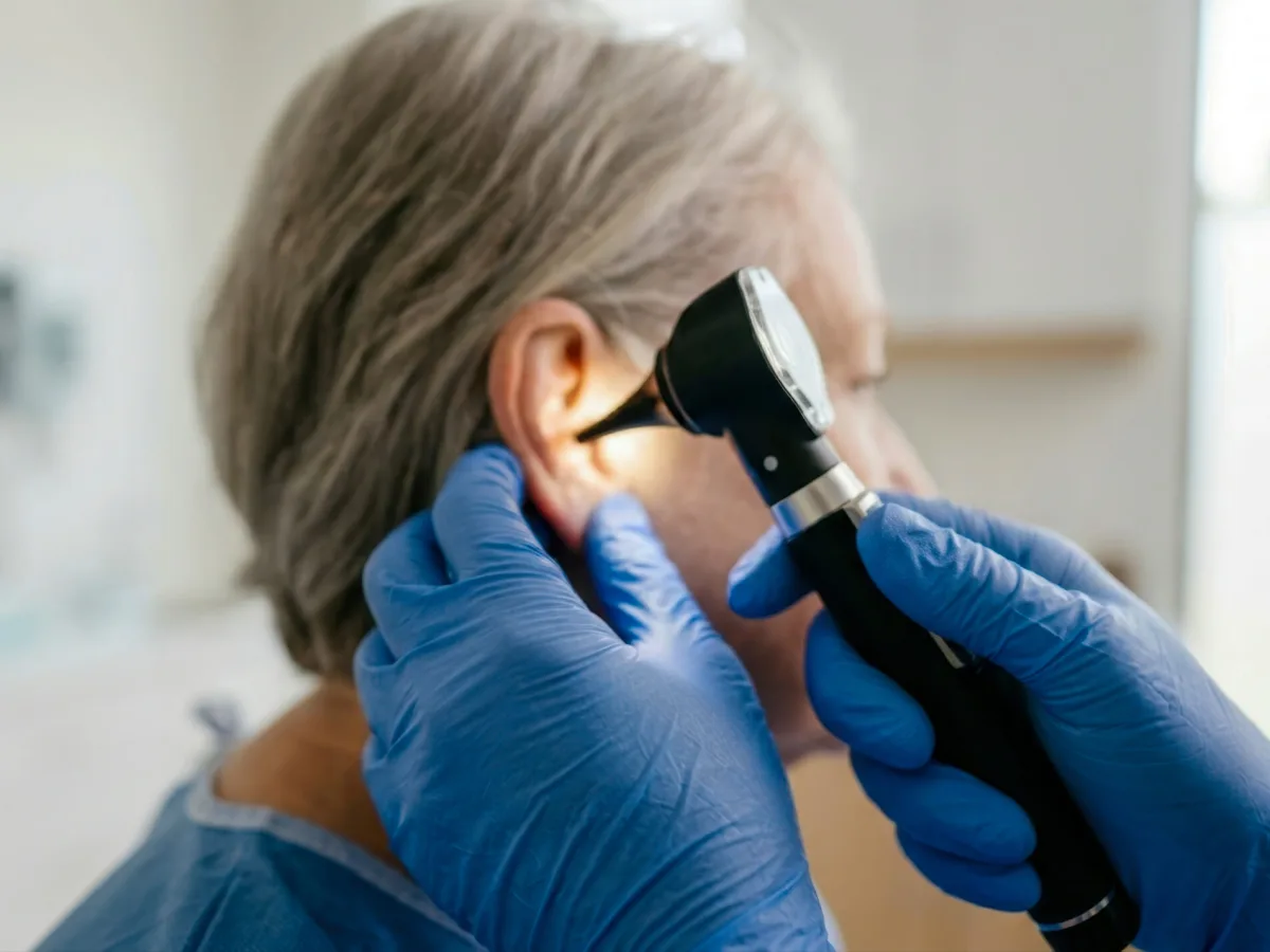 Audiologist examining a patient&rsquo;s ear with an otoscope before earwax removal at The Hearing Team clinic in Birmingham